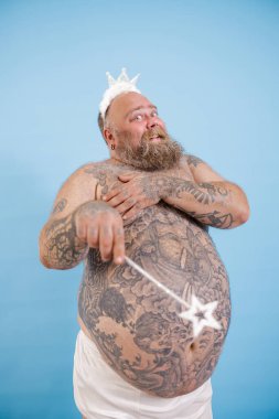 Ayrıca oyuncak taclı ve sihirli sopalı bir adam açık mavi arka planda poz veriyor.