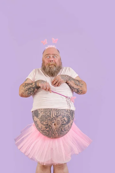 Zszokowany brodaty mężczyzna z nadwagą w stroju bajki na fioletowym tle — Zdjęcie stockowe
