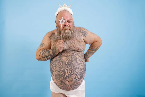 Τατουάζ παχύσαρκος άνθρωπος με στέμμα κοιτάζει μέσα από το αστέρι στο μαγικό ραβδί σε μπλε φόντο — Φωτογραφία Αρχείου