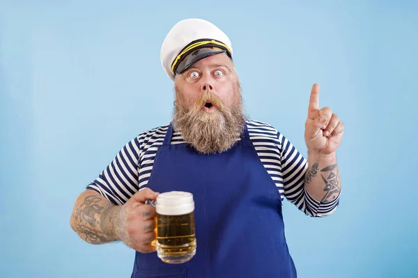 Emotionaler Matrose mit Übergewicht hält Bier und gestikuliert auf hellblauem Hintergrund — Stockfoto