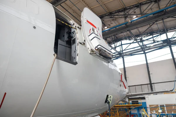 Open aircraft door and cocpit. Passenger airplane on maintenance repair in airport hangar