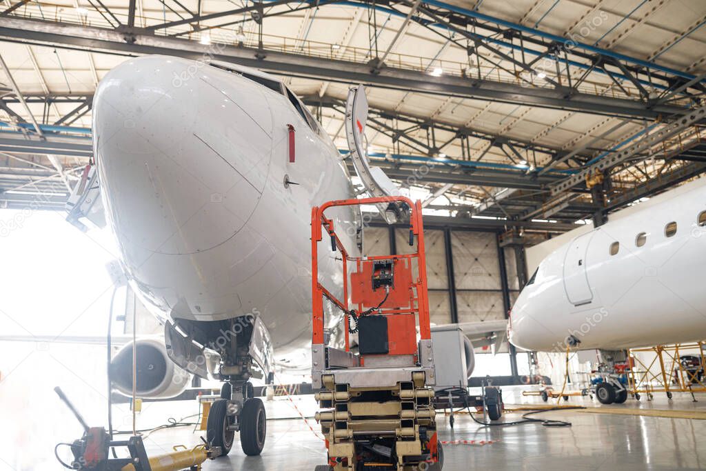 Modern passenger airplane on maintenance repair check in airport hangar indoors