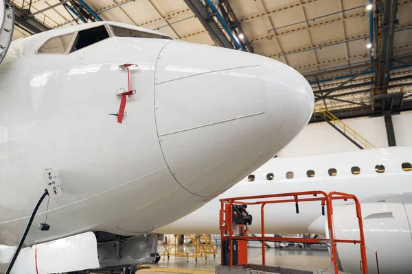 Close up shot of fuselage of modern passenger airplane on maintenance repair check in airport hangar indoors