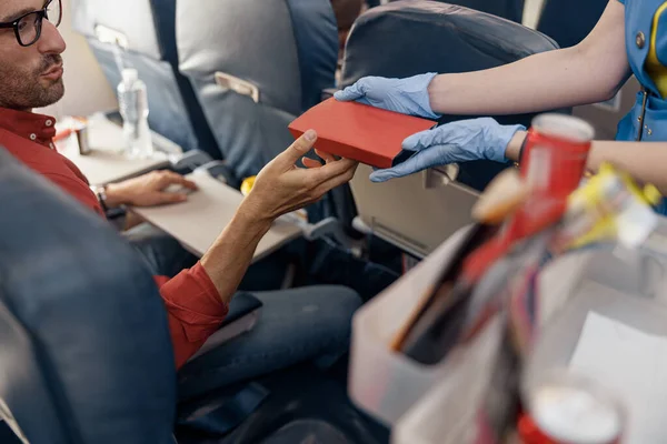 Detailní záběr rukou mužského cestujícího dostat oběd box od ženské letušky servírující jídlo na palubě — Stock fotografie