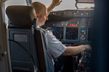Bir uçak kabininde oturan odaklanmış profesyonel pilot, kalkışa hazır.