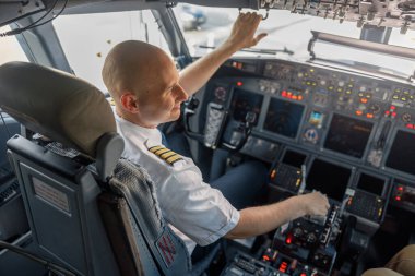 Kalkışa hazır, bir uçak kabininde oturan profesyonel pilotun yüksek açılı görüntüsü.