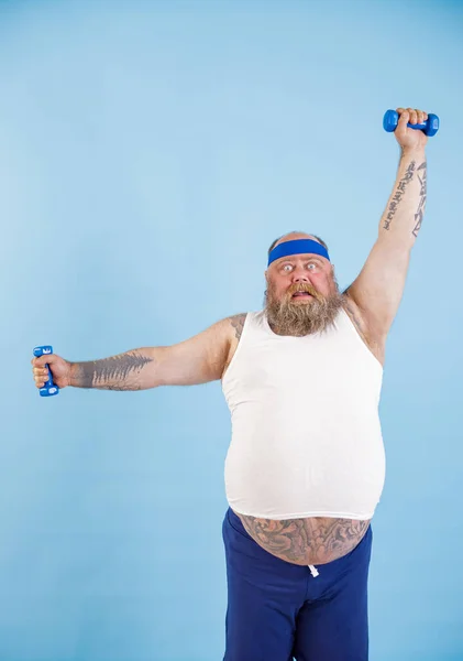 Geschokt zwaarlijvige man doet oefeningen met halters training hard in de studio — Stockfoto