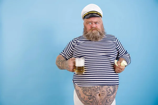 Grappig zwaarlijvige zeeman houdt roken pijp en bier grimacing op lichtblauwe achtergrond — Stockfoto