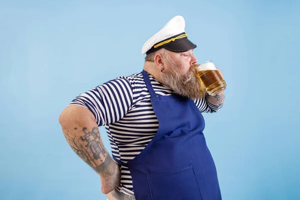 Happy matuer plus size man in matrozenpak drinkt vers bier op lichtblauwe achtergrond — Stockfoto