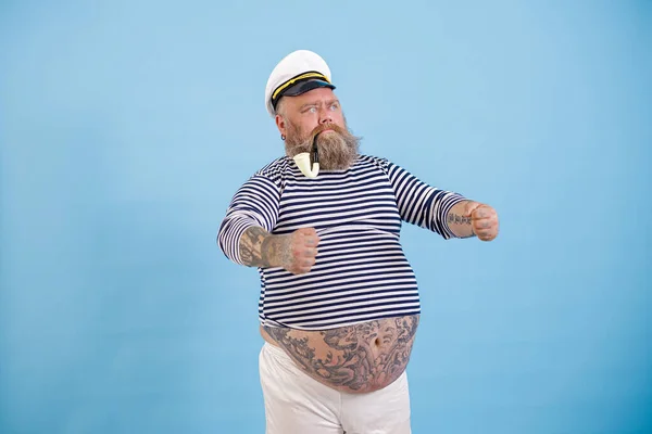 Übergewichtiger Kapitän mit Vintage-Raucherpfeife hält unsichtbares Steuer auf hellblauem Hintergrund — Stockfoto