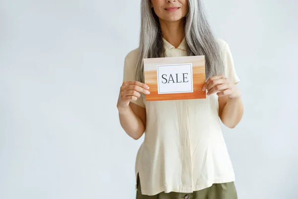 Feliz mujer de mediana edad sostiene colorido cartel de venta sobre fondo gris claro —  Fotos de Stock