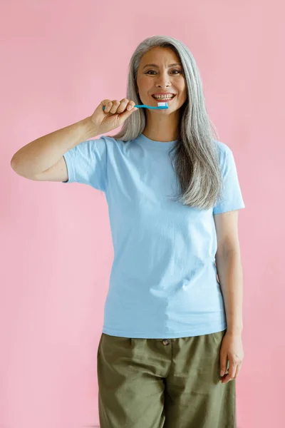 在粉色背景下，正长发的成熟亚洲型牙刷 — 图库照片