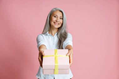 Güzel orta yaşlı Asyalı kadın, pembe arka planda uzun beyaz saçlı hediye.