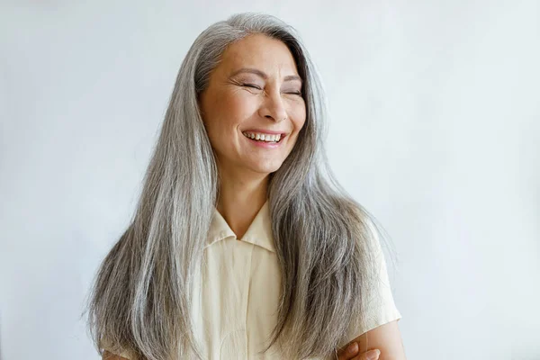 Retrato de mujer asiática sonriente con el pelo alzado y brazos cruzados sobre fondo gris — Foto de Stock