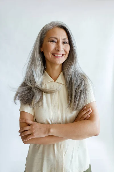 Retrato de modelo feminino asiático com cabelos longos e cinza e braços cruzados em fundo claro — Fotografia de Stock