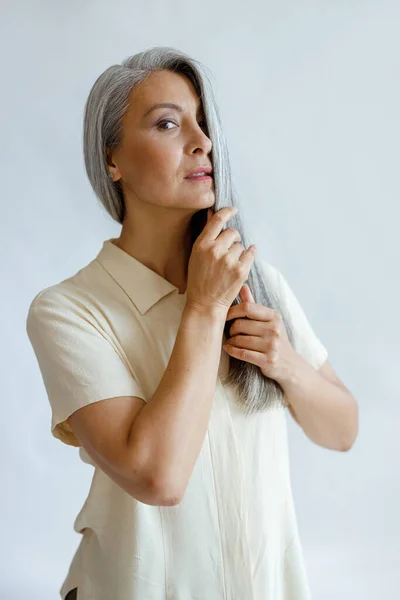 Aantrekkelijk volwassen Aziatisch model in huiden helft van gezicht met zilver haar op lichte achtergrond — Stockfoto