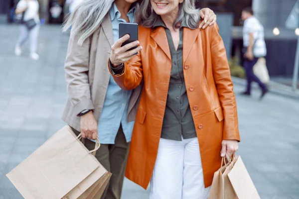 Señora mayor en chaqueta de cuero y compañero de compras tomar selfie en la calle moderna de la ciudad —  Fotos de Stock