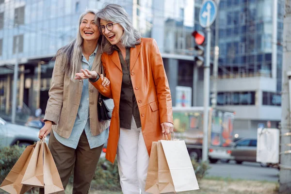 Mujeres bastante maduras con muchas bolsas de compras se ríen en la calle de la ciudad —  Fotos de Stock