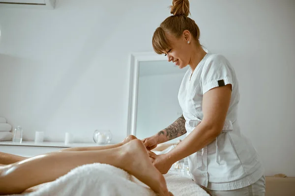 Profesional caucásico especialista está haciendo mensaje pierna en moderno salón minimalista — Foto de Stock