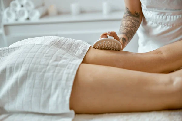 Especialista femenina confiable está haciendo masaje de piernas anticelulíticas a hermosa cliente femenina caucásica saludable — Foto de Stock