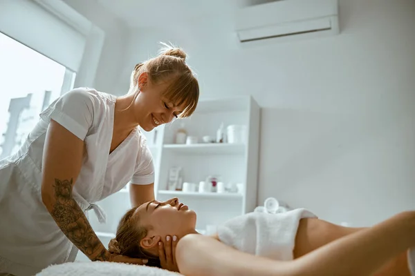 Adulto especialista do sexo feminino está fazendo massagem no pescoço para um jovem cliente feminino bonito natural — Fotografia de Stock