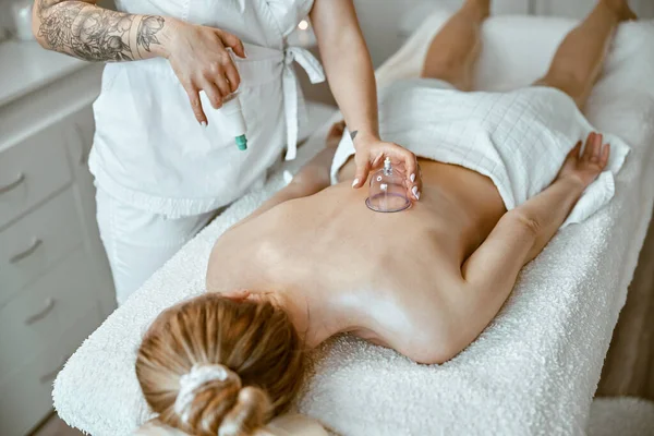 Especialista profissional feminino está fazendo terapia de copos na parte de trás da bela senhora caucasiana — Fotografia de Stock