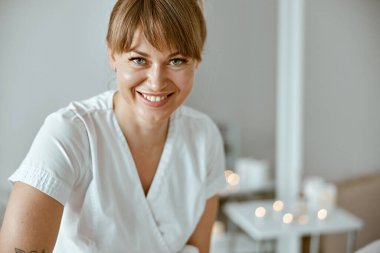 Kendine güvenen kadın uzman, minimalist spa salonundaki güzel beyaz kadın için vücut masajı yapıyor.
