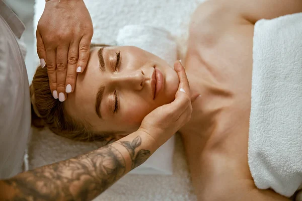 Terapeut gör ansikte avkopplande massage till en ung kvinna i moderna wellness skåp — Stockfoto