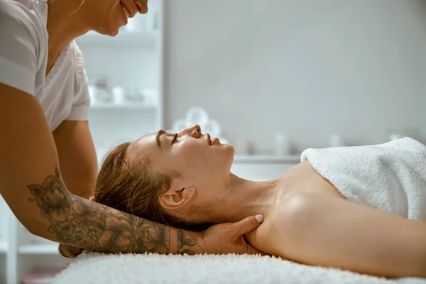 Vuxen kvinnlig specialist gör hals massage till en ung naturlig skönhet kvinnlig klient — Stockfoto