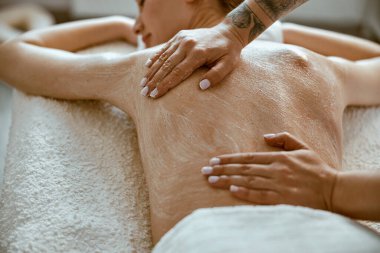 Kendine güvenen kadın uzman, minimalist spa salonundaki güzel beyaz kadın için vücut masajı yapıyor.