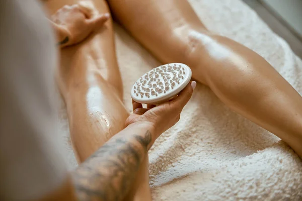 Especialista feminina confiante está fazendo anticelulite massagem perna para belo cliente feminino caucasiano saudável — Fotografia de Stock