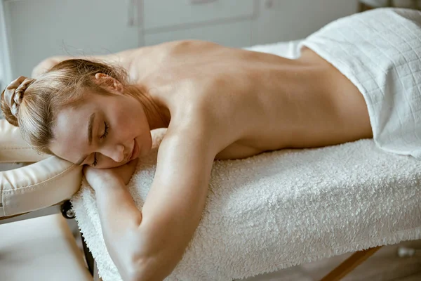 Schöne schlanke kaukasische Frau entspannt sich auf Therapeutentisch im Wellness-Salon — Stockfoto