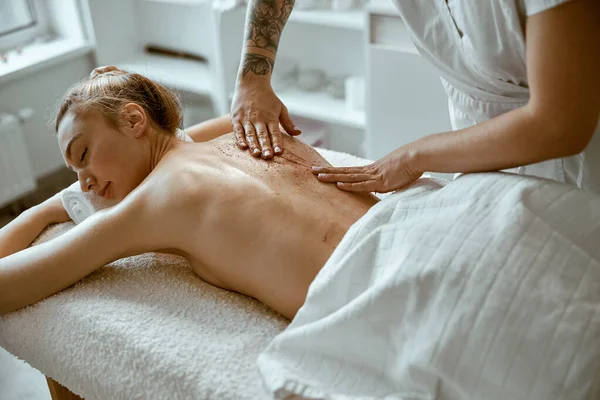 Säker kvinnlig specialist gör avkopplande kroppsmassage för vackra smala kaukasiska dam på minimalistisk spa salong — Stockfoto