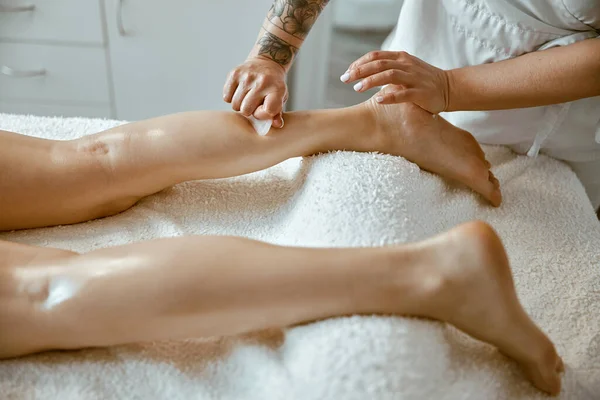 Masajcı kadın modern salonda profesyonel bacak masajı yapıyor. — Stok fotoğraf