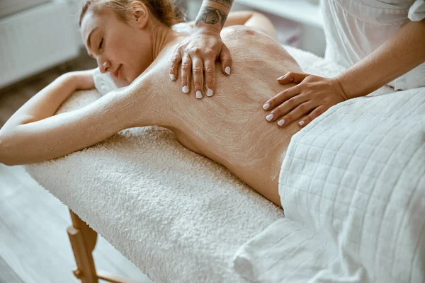 Especialista femenino confiado está haciendo masaje relajante del cuerpo para la señora hermosa delgada caucásica en el salón de spa minimalista — Foto de Stock