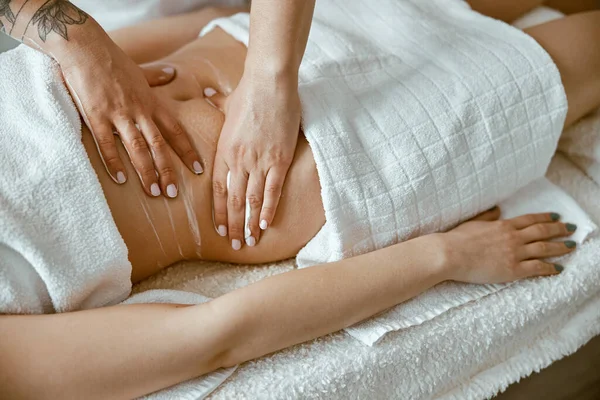 Professionell massage gör magmassage till ung kvinnlig klient i modern wellness salong — Stockfoto