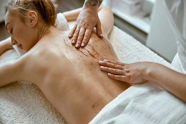 Fiducioso specialista femminile sta facendo massaggio corpo rilassante per bella signora caucasica sottile al salone spa minimalista — Foto Stock