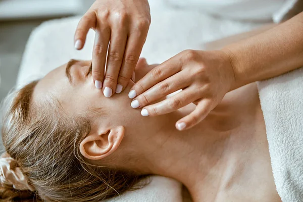 Terapeut gör ansikte avkopplande massage till en ung kvinna i moderna wellness skåp — Stockfoto