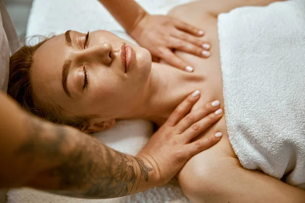 Terapeuta está fazendo cara massagem relaxante para uma jovem mulher no armário de bem-estar moderno — Fotografia de Stock