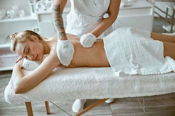 Especialista femenino confiado está haciendo masaje relajante del cuerpo para la señora hermosa delgada caucásica en el salón de spa minimalista — Foto de Stock