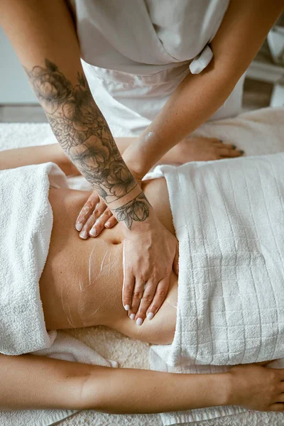 Professionell massage gör magmassage till ung kvinnlig klient i modern wellness salong — Stockfoto