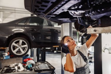 Yetenekli bir tamirci, bir otomotiv atölyesindeki bir aracı inceliyor ve uzmanlığını ve bağlılığını gösteriyor.