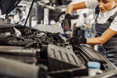 Çok yetenekli ve kendini işine adamış bir kadın tamirci titizlikle bir motoru tamir ediyor ve otomobil servisinde uzmanlık gösteriyor.