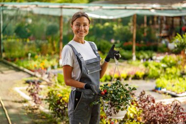 Neşeli bir bahçıvan gururla sera ortamının zemininde canlı çiçekler sergiliyor.