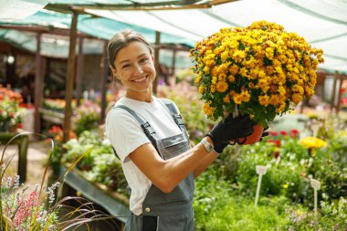 Neşeli bir bahçıvan gururla serada canlı bir buket çiçek sergiliyor.