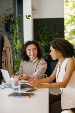 Meslektaşlar dijital olarak işbirliği yapıyor, iki iş arkadaşı teknoloji araçları kullanarak proje iyileştirmelerini tartışıyor