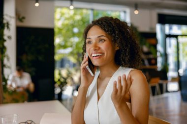Hevesli bayan müşteri hizmetleri temsilcisi müşteriyle sıcak bir şekilde konuşurken, aynı zamanda gülümsüyor.