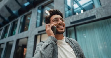 Erkek profesyonel telefonda gülümsüyor, öncelikleri koordine ediyor ve görevleri iyimser bir şekilde görüşüyor.