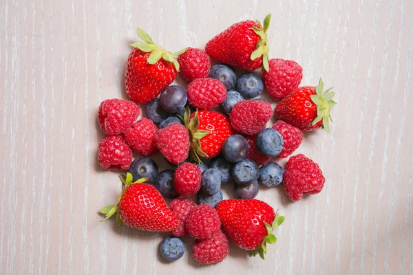 Ahududu, çilek ve bilberry ahşap arka plan üzerinde