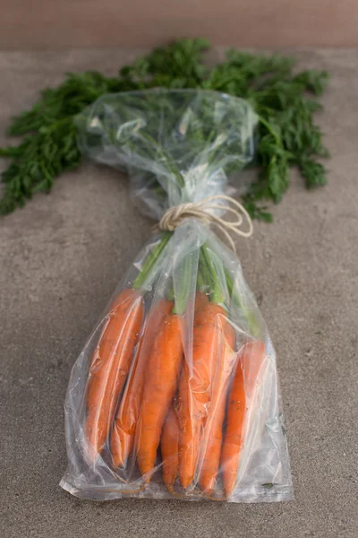 Carrot on the stone background in the transparent pack — Stock Photo, Image